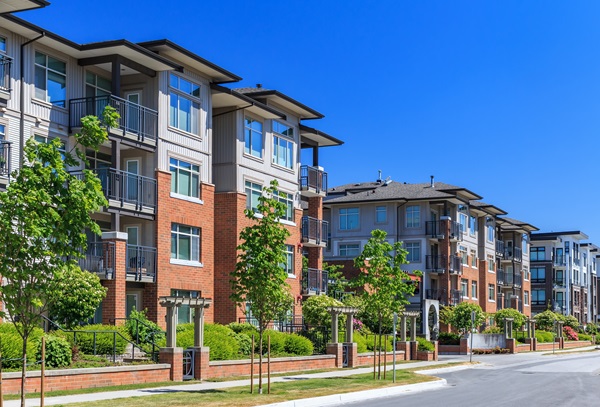 A row of apartment buildings with red brick siding on the bottom and white siding on the upper floors.