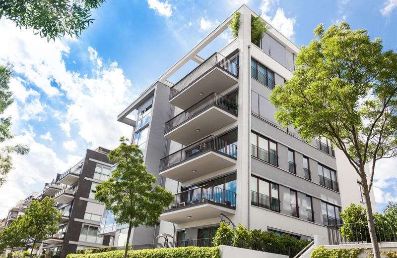 modern apartment complex with balconies and a vibrant blue sky